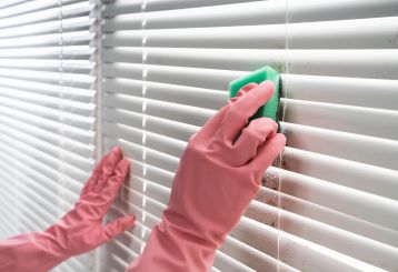 Person using a microfiber cloth to clean blinds