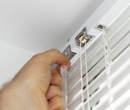 A male installing Venetian blinds