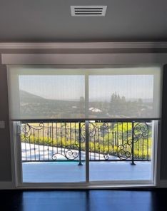 Living room in San Jose featuring sheer roller shades partially drawn over patio doors, allowing sunlight while maintaining privacy.